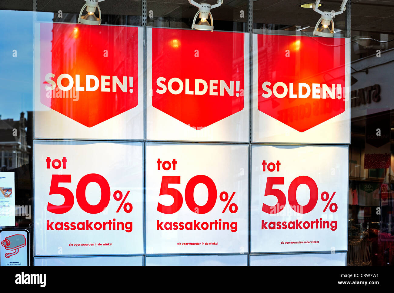 Avis d'escompte montrant la moitié : déductions dans vitrine de magasin pendant les soldes d'été dans la rue commerçante, Belgique Banque D'Images