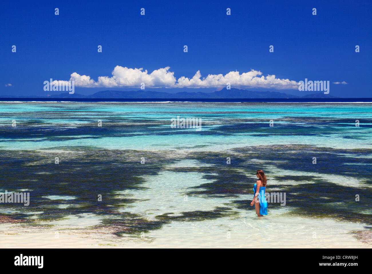 La femme en bleu sarong patauge dans les eaux près de Anse Source d'argent sur La Digue aux Seychelles Banque D'Images