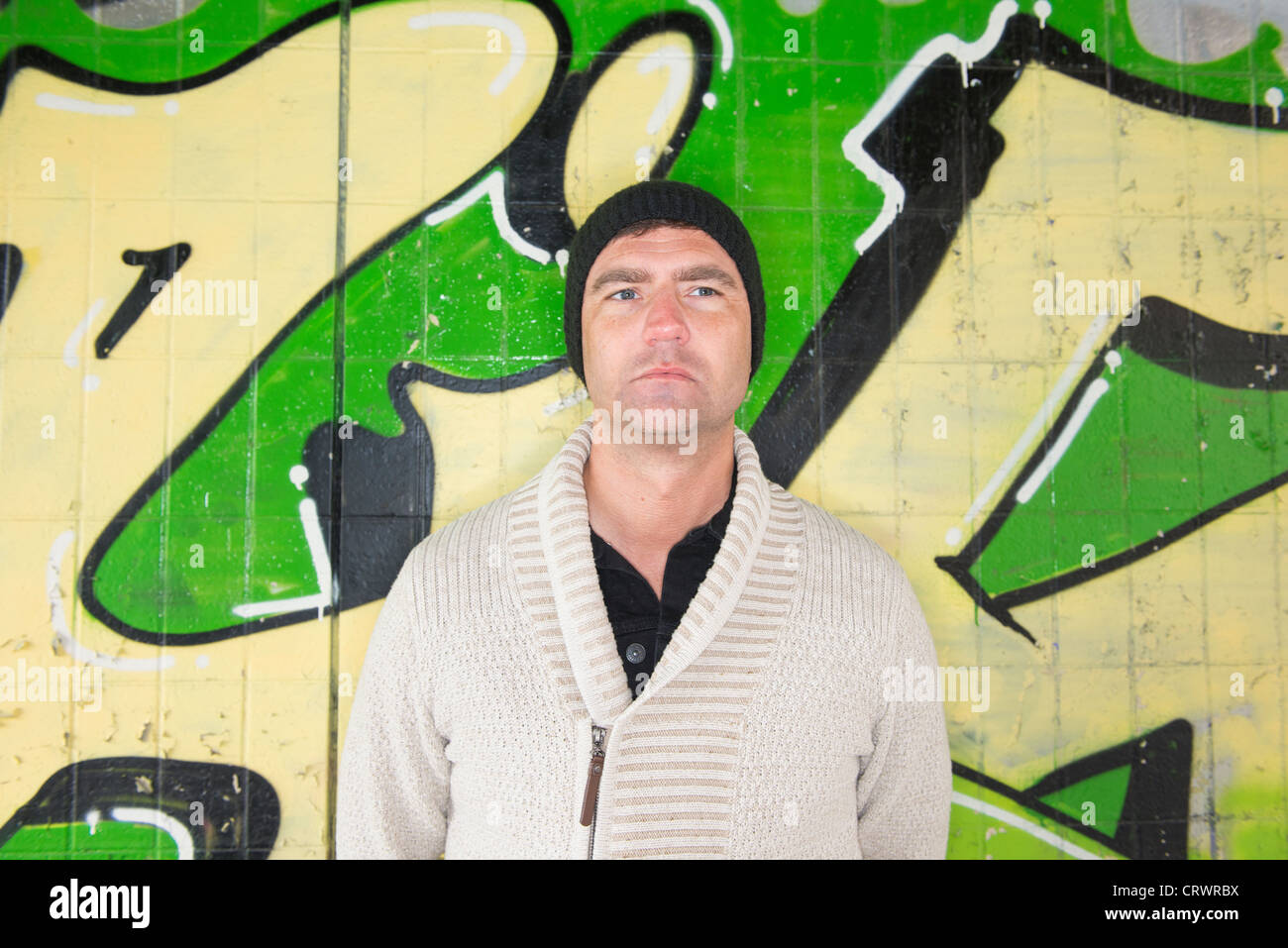 Mid adult man avec son dos contre un mur plein de graffiti Banque D'Images