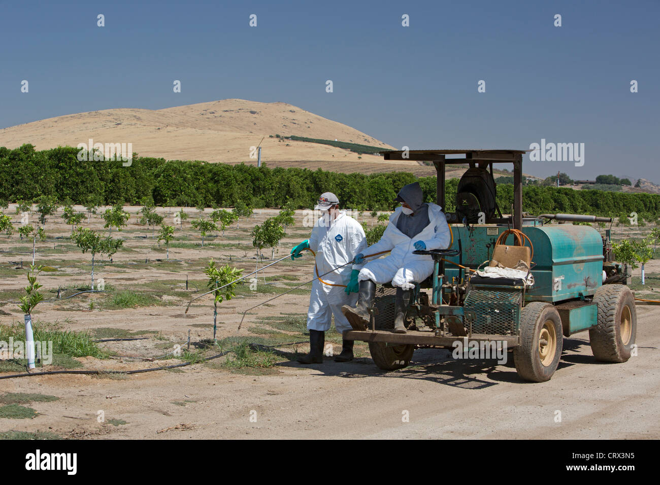Woodlake, Californie - les travailleurs dans des vêtements de pesticides s'applique à un champ dans la vallée de San Joaquin. Banque D'Images