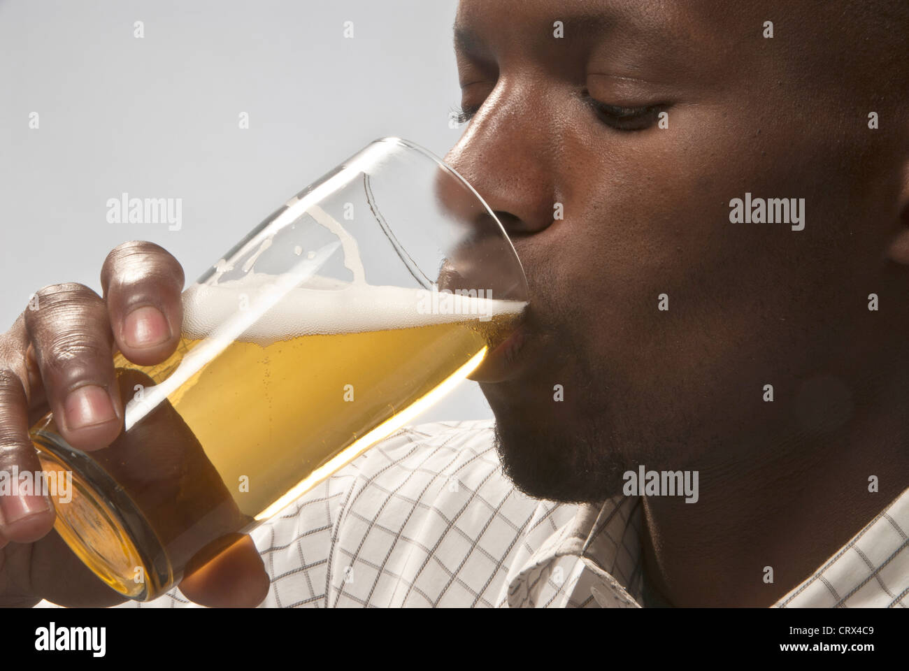 L'homme boit une bière de type lager froide dans un verre. Banque D'Images