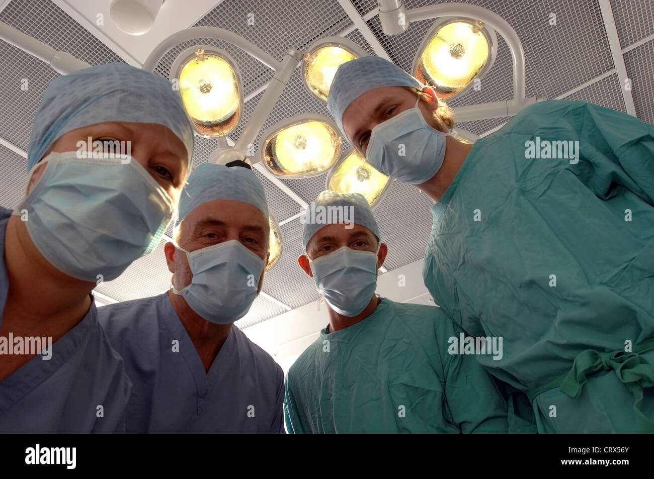 Vue d'un patient d'une équipe de chirurgiens masqués sous des lampes dans un théâtre d'opération des hôpitaux. Banque D'Images