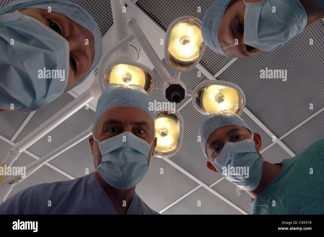 Vue d'un patient d'une équipe de chirurgiens masqués sous des lampes dans un théâtre d'opération des hôpitaux. Banque D'Images