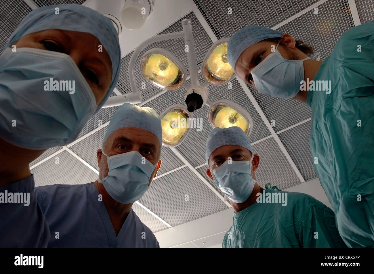 Vue d'un patient d'une équipe de chirurgiens masqués sous des lampes dans un théâtre d'opération des hôpitaux. Banque D'Images