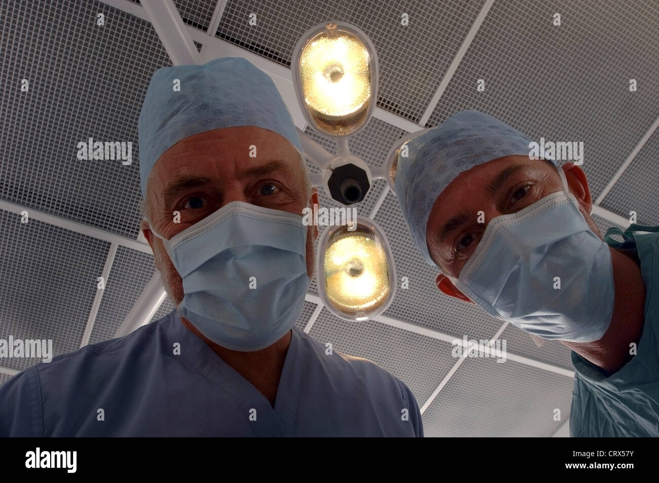 Vue d'un patient d'une équipe de chirurgiens masqués sous des lampes dans un théâtre d'opération des hôpitaux. Banque D'Images
