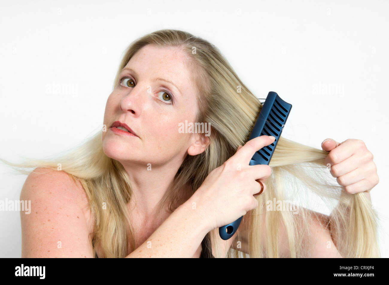 Portrait of attractive young woman brushing sèche sur un fond blanc. Banque D'Images