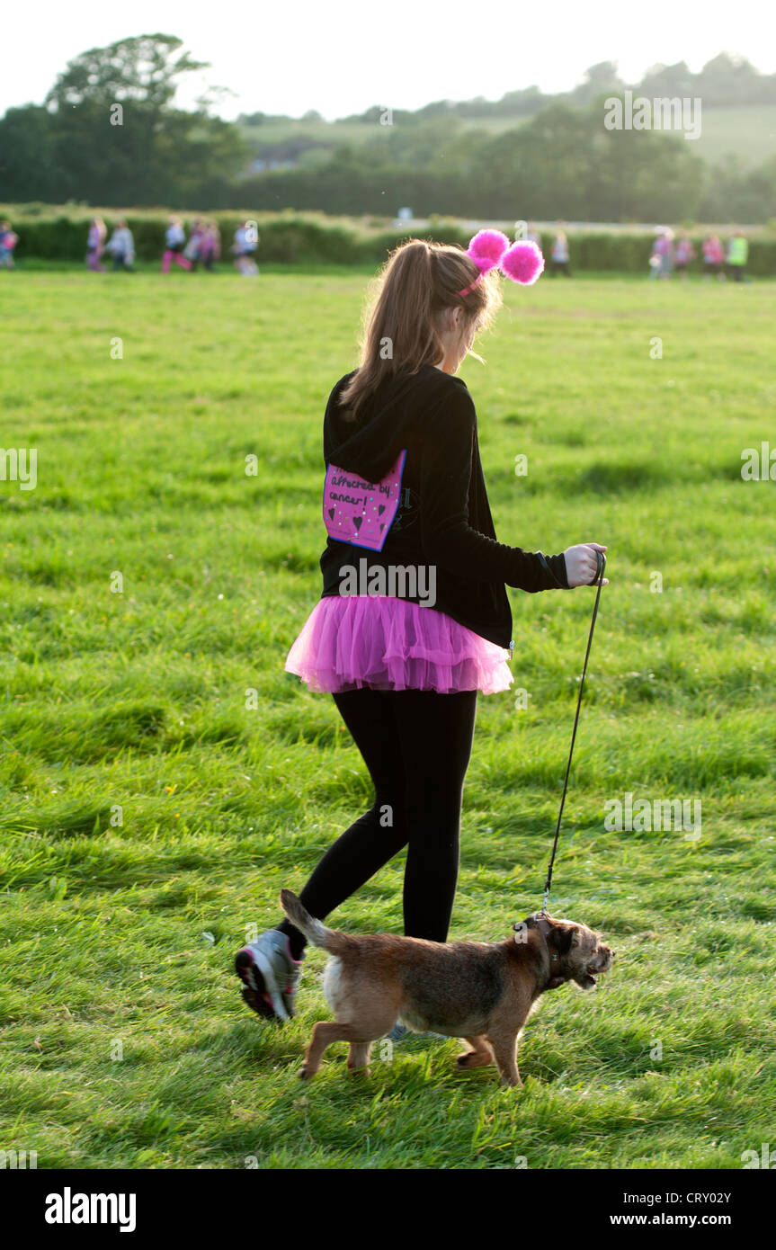 Jeune femme avec chien dans la course pour la vie à l'Hippodrome de Stratford. Banque D'Images