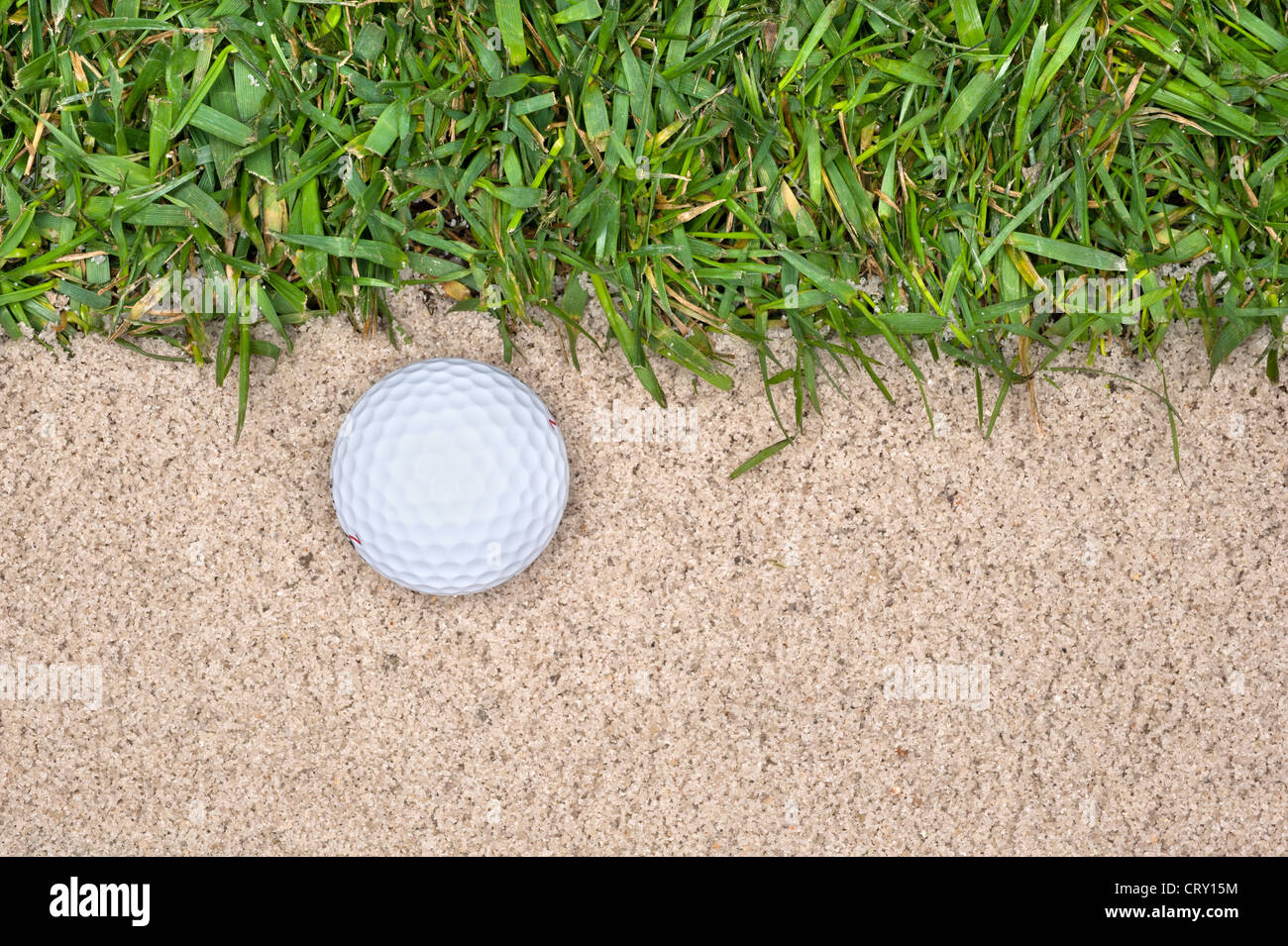 Une balle de golf dans une fosse de sable à côté de la dure met en évidence les erreurs qu'on peut faire jouer le jeu. Banque D'Images