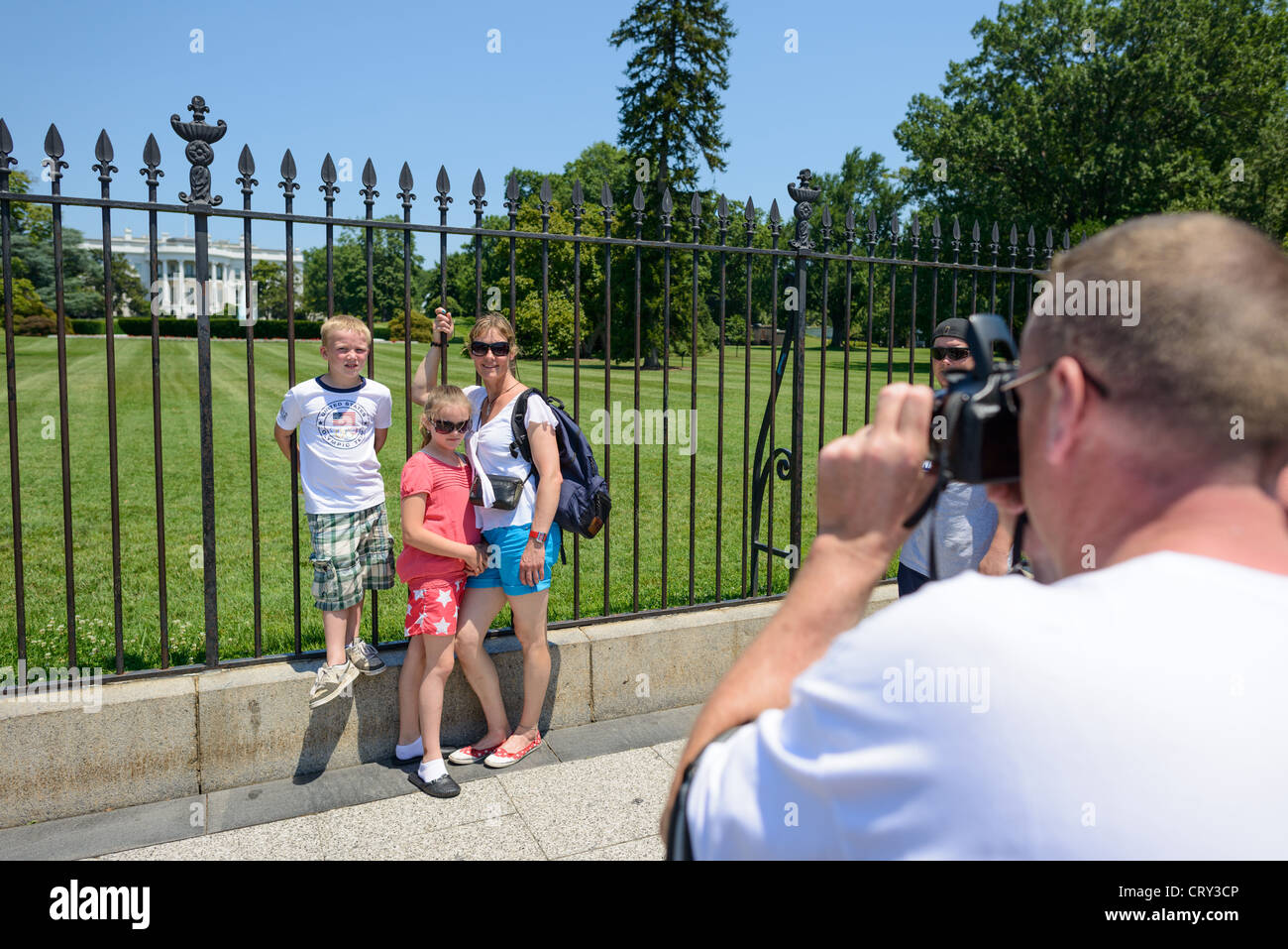 WASHINGTON DC — Une famille pose pour une photographie devant la clôture en fer forgé sur le côté sud de la Maison Blanche à Washington DC. Ce spot photo populaire offre aux visiteurs une vue sur le Portique Sud et la pelouse Sud de la résidence présidentielle. La Maison Blanche, située au 1600 Pennsylvania Avenue, a été la maison officielle et le lieu de travail de tous les présidents américains à l'exception de George Washington depuis son achèvement en 1800. Banque D'Images
