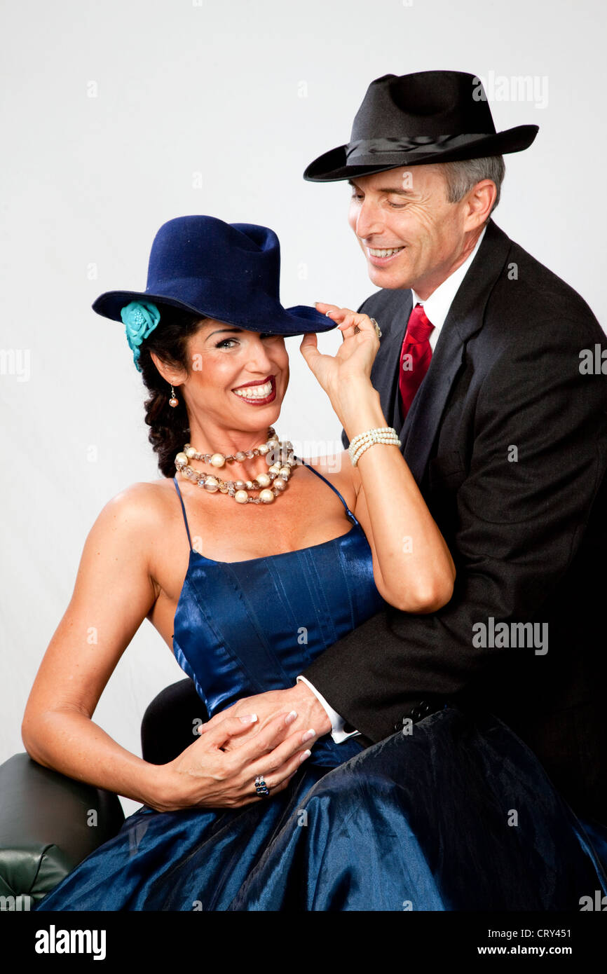 La maturité, romantic couple en tenue de soirée, la femme dans une robe  bleue et un chapeau pendant que son homme porte un costume, cravate rouge  et un chapeau avec Photo Stock -