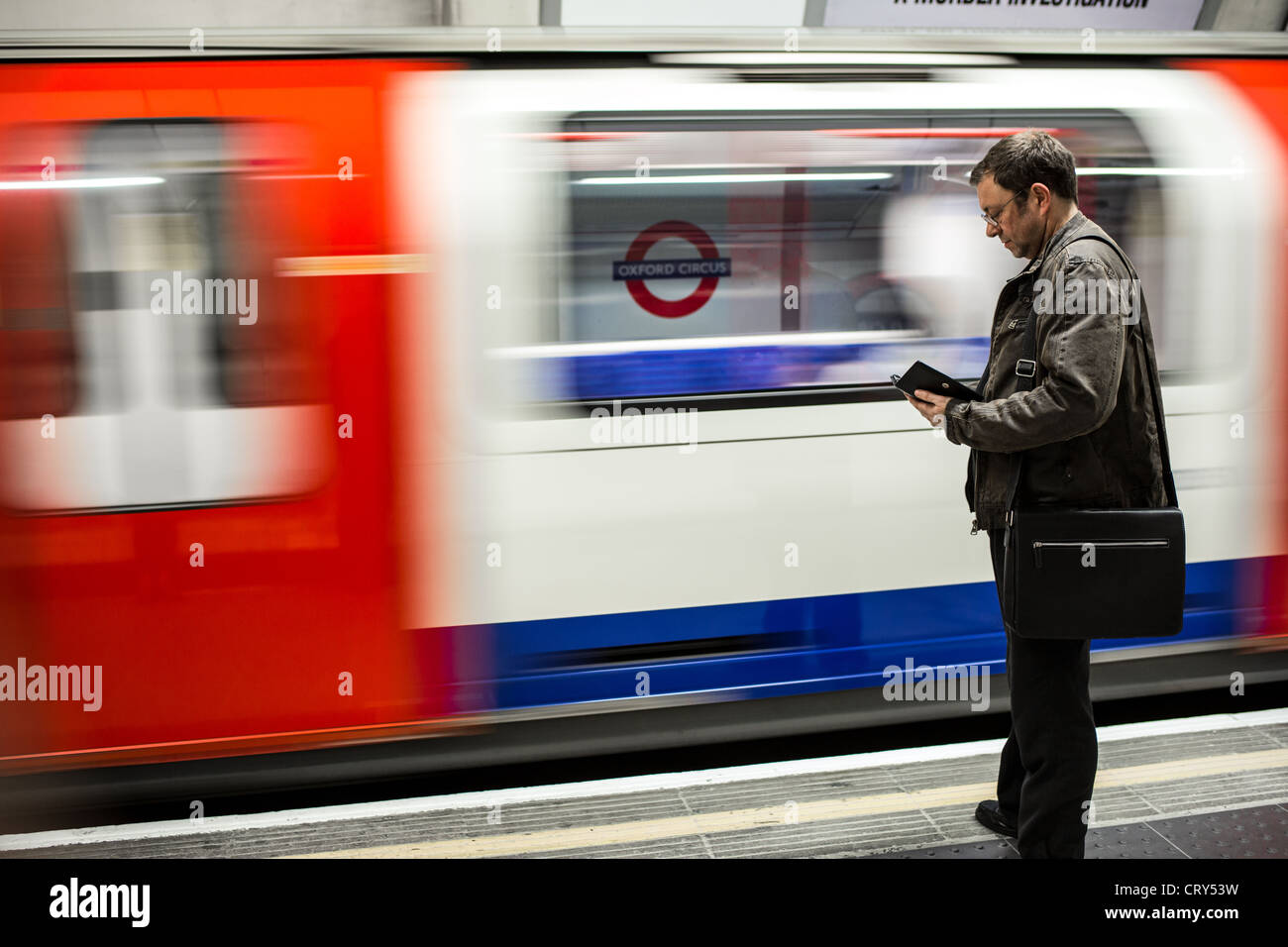 Un homme lit son Kindle en attendant le prochain train. L'image a été prise à l'arrêt du Cercle d'Oxford London Tube. Banque D'Images