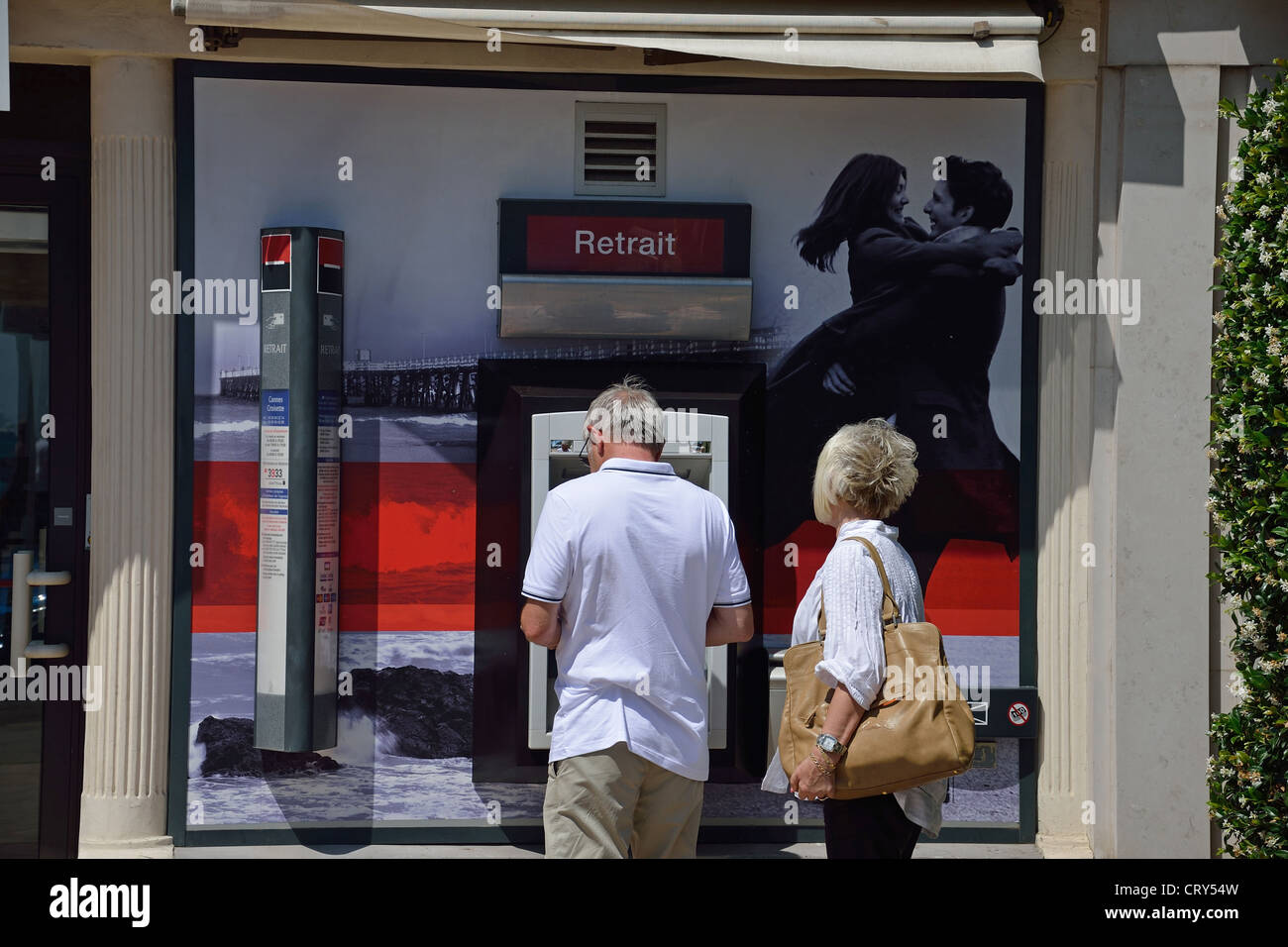 Couple en utilisant un guichet automatique du Boulevard de la Croisette, Cannes, Côte d'Azur, Alpes-Maritimes, Provence-Alpes-Côte d'Azur, France Banque D'Images