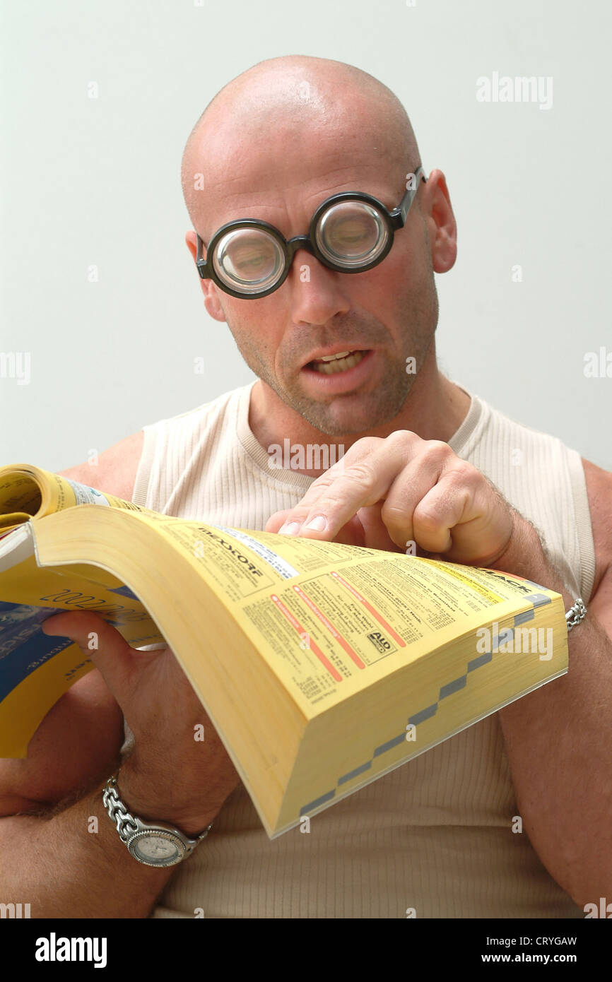 Homme avec verres épais essaie de lire les Pages Jaunes Banque D'Images