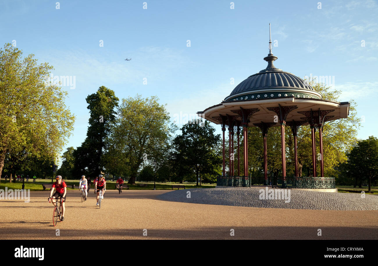 Les cyclistes vélo passé le kiosque au lever du soleil, Clapham Common, London UK Banque D'Images