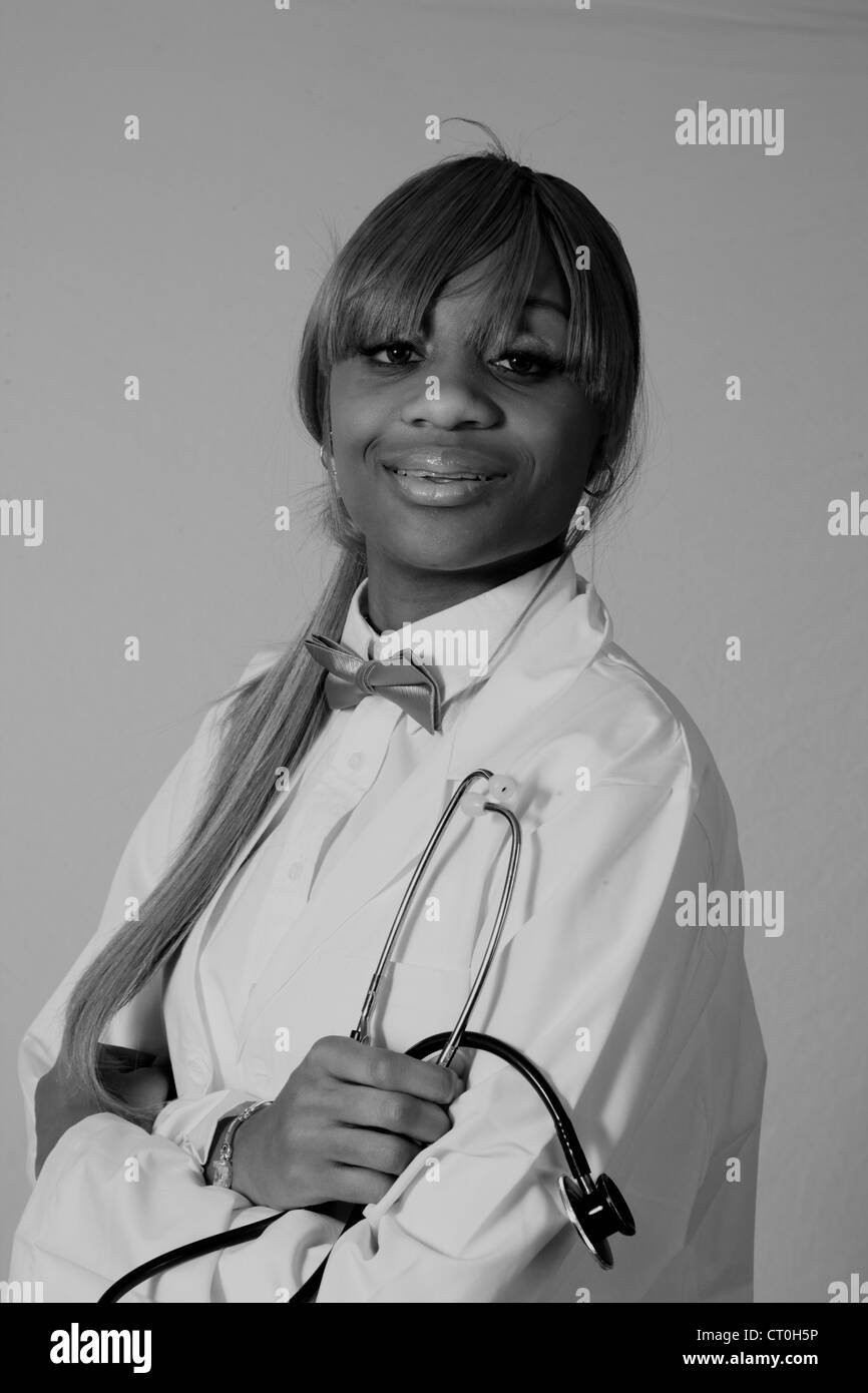 Jolie jeune femme black health care worker in lab coat avec un stéthoscope, regardant la caméra et sourit. Banque D'Images