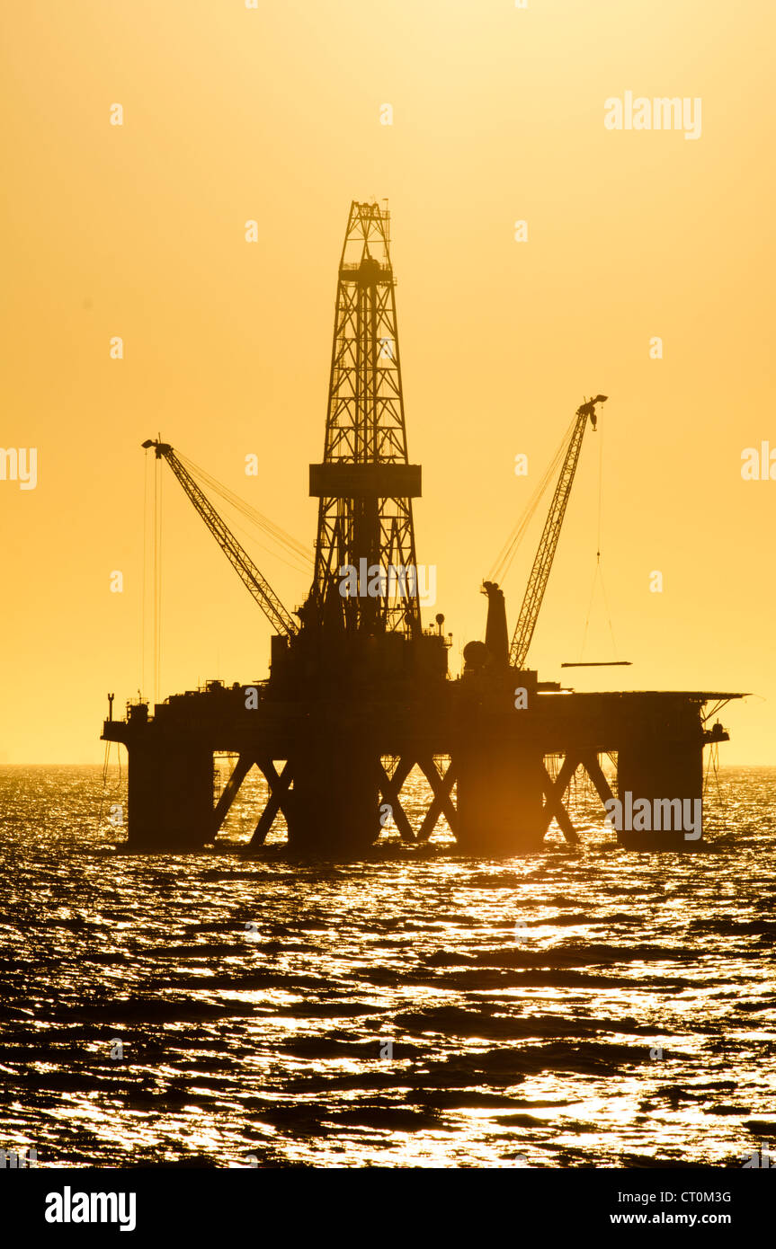 Silhouette d'offshore oil drilling rig au moment de coucher de soleil. Côte de l'état de Rio de Janeiro, le sud-est du Brésil. Banque D'Images