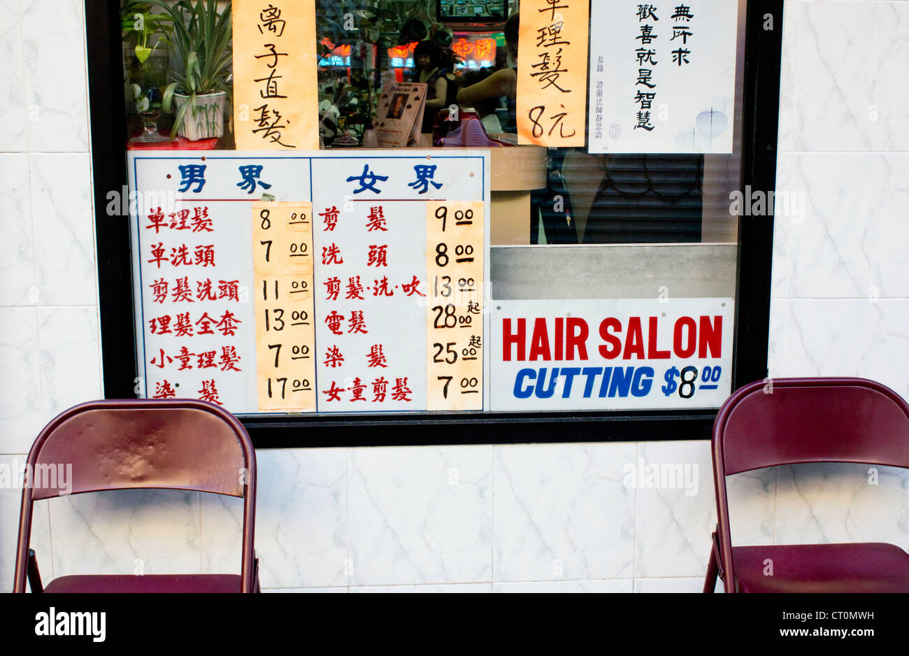 Une liste de prix des services dans la fenêtre d'un salon de coiffure de Chinatown à New York City Banque D'Images