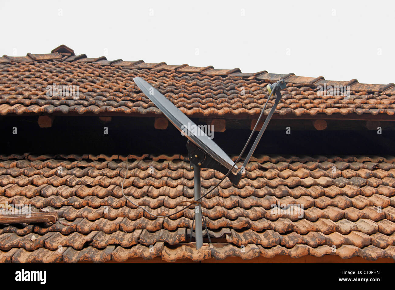 Une antenne parabolique d'un poste de télévision traditionnel sur un toit en pente fait Manglori avec carreaux, Ratnagiri, Maharashtra, Inde Banque D'Images