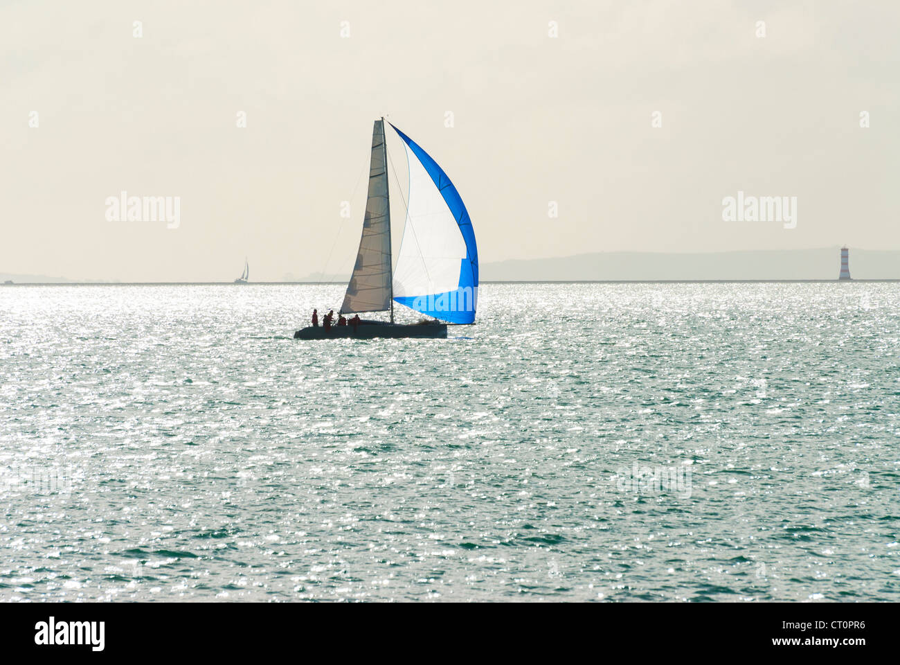 Un seul bateau à voile avec un spi de couleur bleu et blanc d'exécution. Banque D'Images