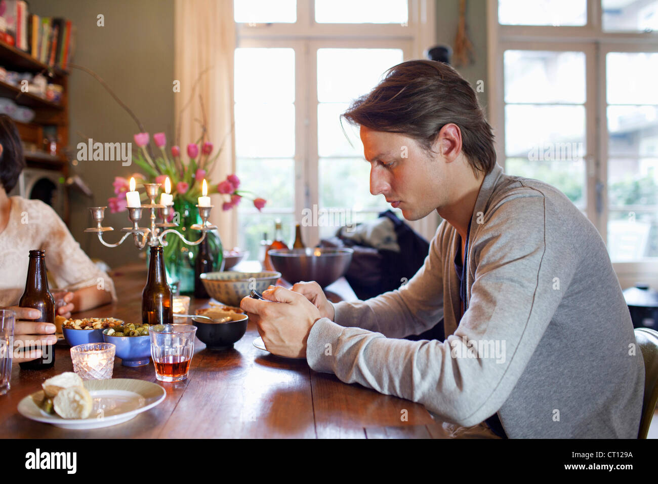 Man using cell phone at dinner table Banque D'Images