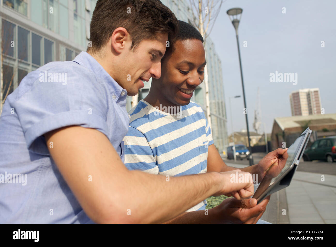 Men using tablet computer on street Banque D'Images