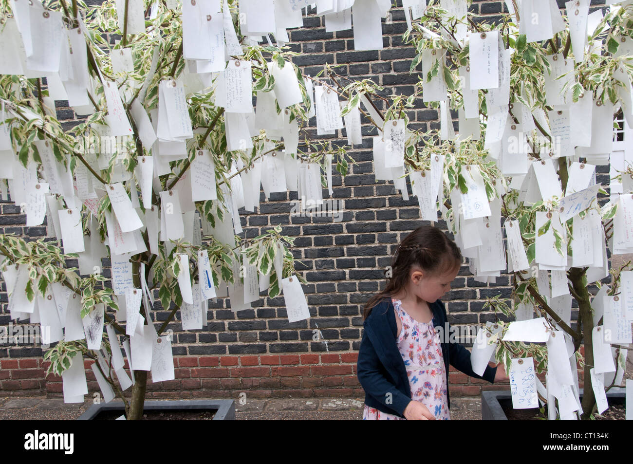 Serpentine Gallery - arbre des désirs par Yoko Ono - enfant l'examen des étiquettes avec des souhaits écrits sur eux Banque D'Images
