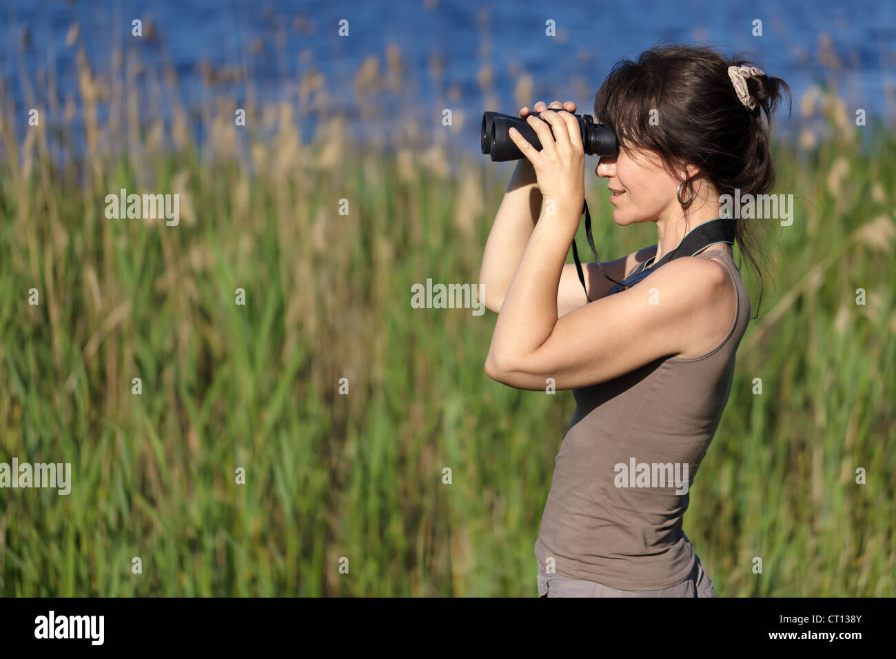 Femme regardant avec des jumelles de la faune dans la zone de marais Banque D'Images