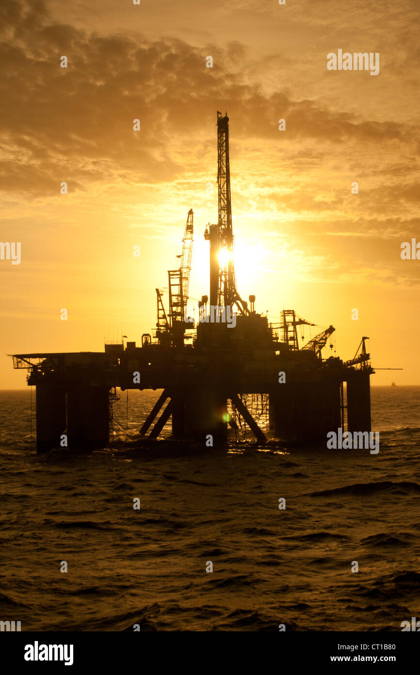 Silhouette d'offshore oil drilling rig au moment de coucher de soleil. Côte de l'état de Rio de Janeiro, le sud-est du Brésil. Banque D'Images