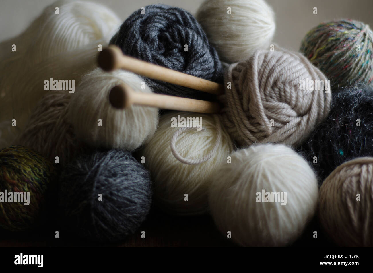 Libre de balles de laine dans des tons de couleurs ocre, avec des aiguilles à tricoter en bois. Banque D'Images