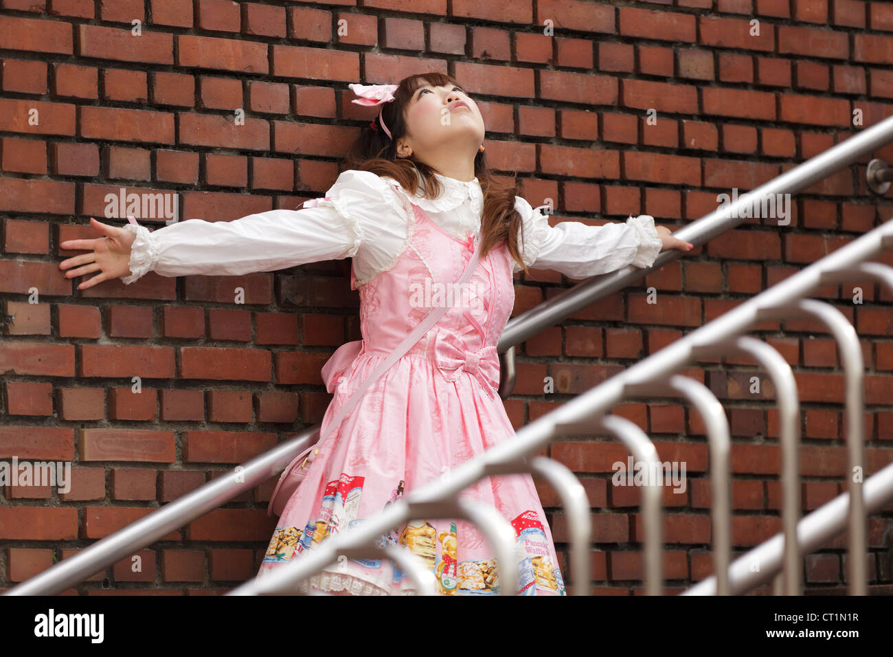 Cosplay lolita japonais appuyé contre un mur de briques dans les escaliers Banque D'Images