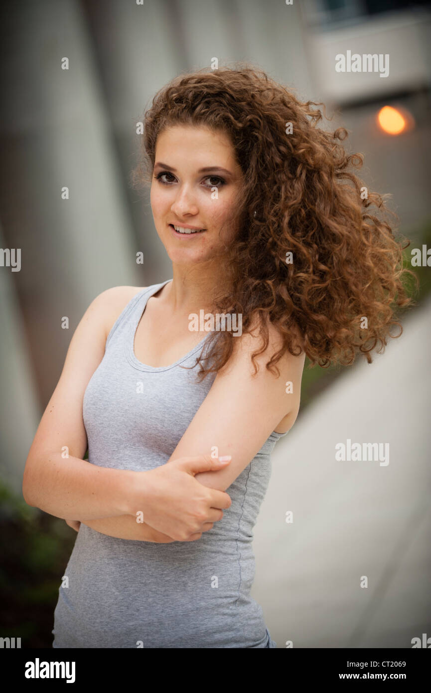 Un jeune 20 ans attrayant slim smiling happy woman fille avec de longs cheveux bruns bouclés UK Banque D'Images