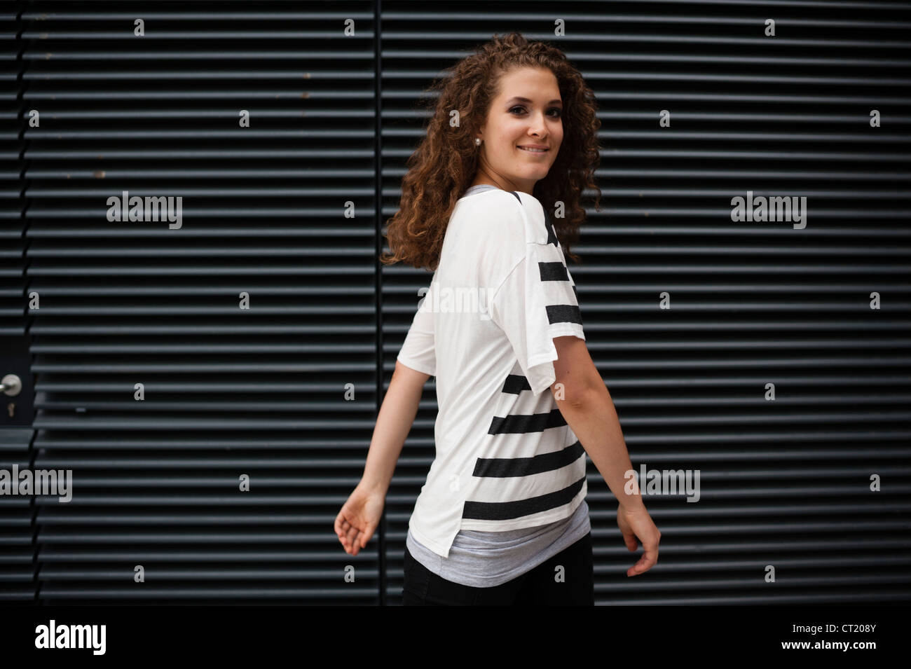 Un jeune 20 ans jolie femme slim girl wearing a black and white striped t-shirt long avec les cheveux bruns bouclés UK Banque D'Images