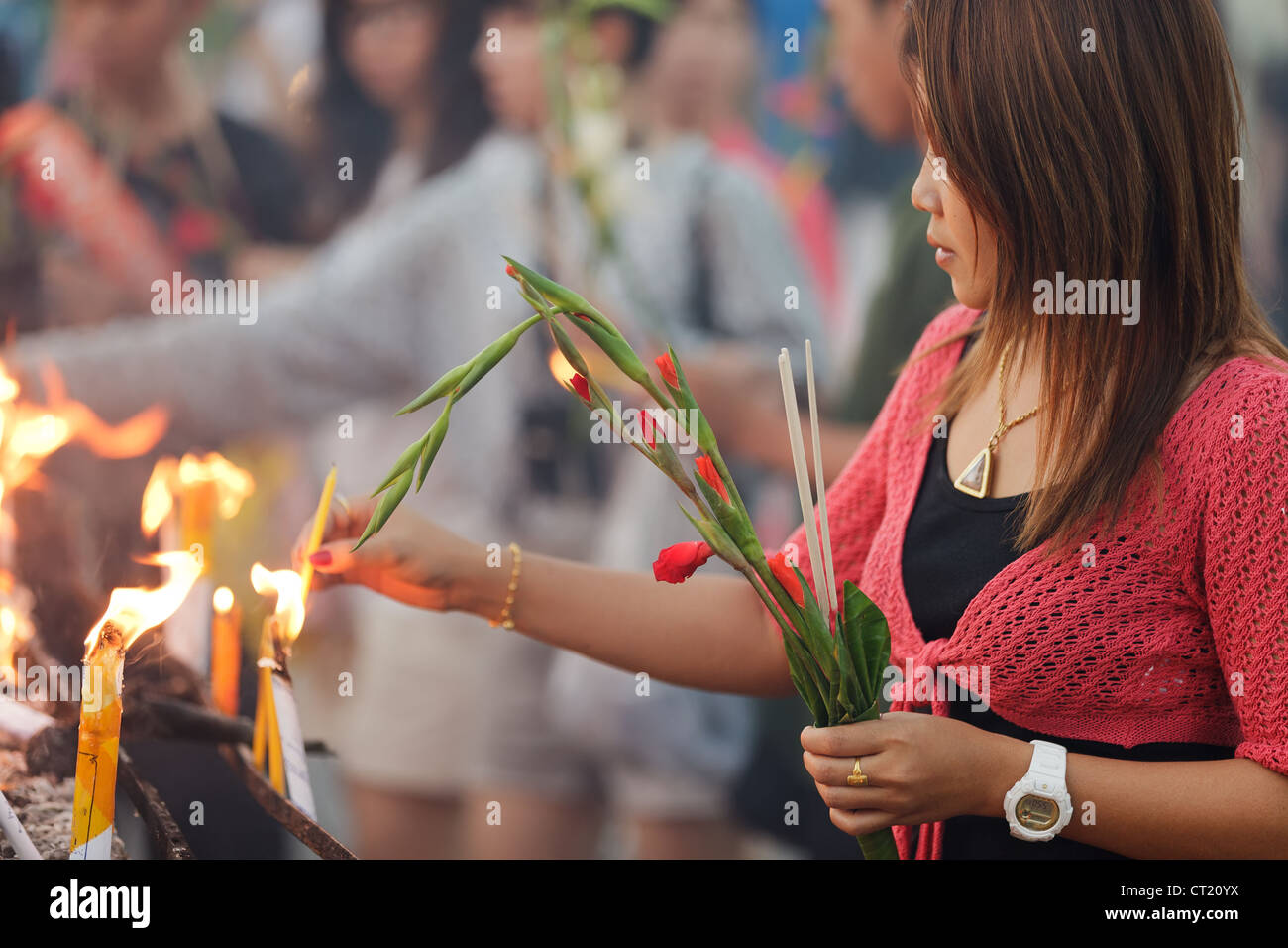 Buddhist woman holding flower glaïeul et allumer l'encens en bâton temple thaïlandais Banque D'Images