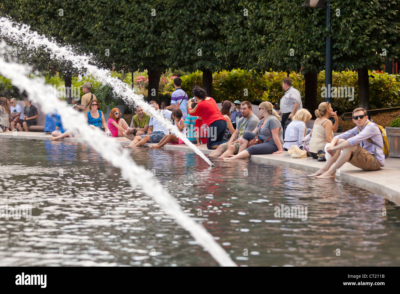 Les gens assis dans une fontaine publique Banque D'Images