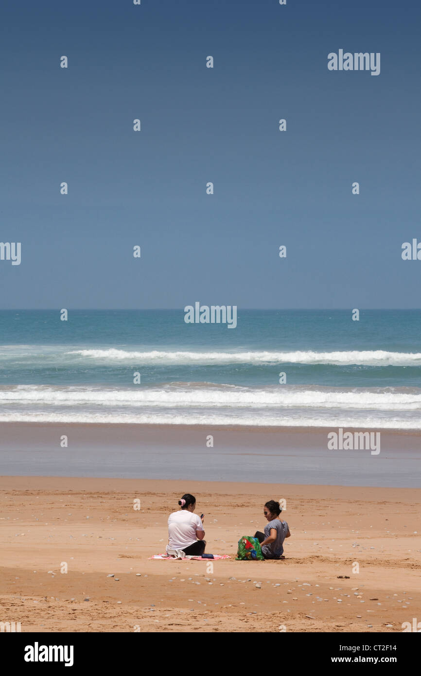 Deux femmes assis sur une plage déserte près d'Agadir sur la côte Atlantique, le Maroc, l'Afrique Banque D'Images