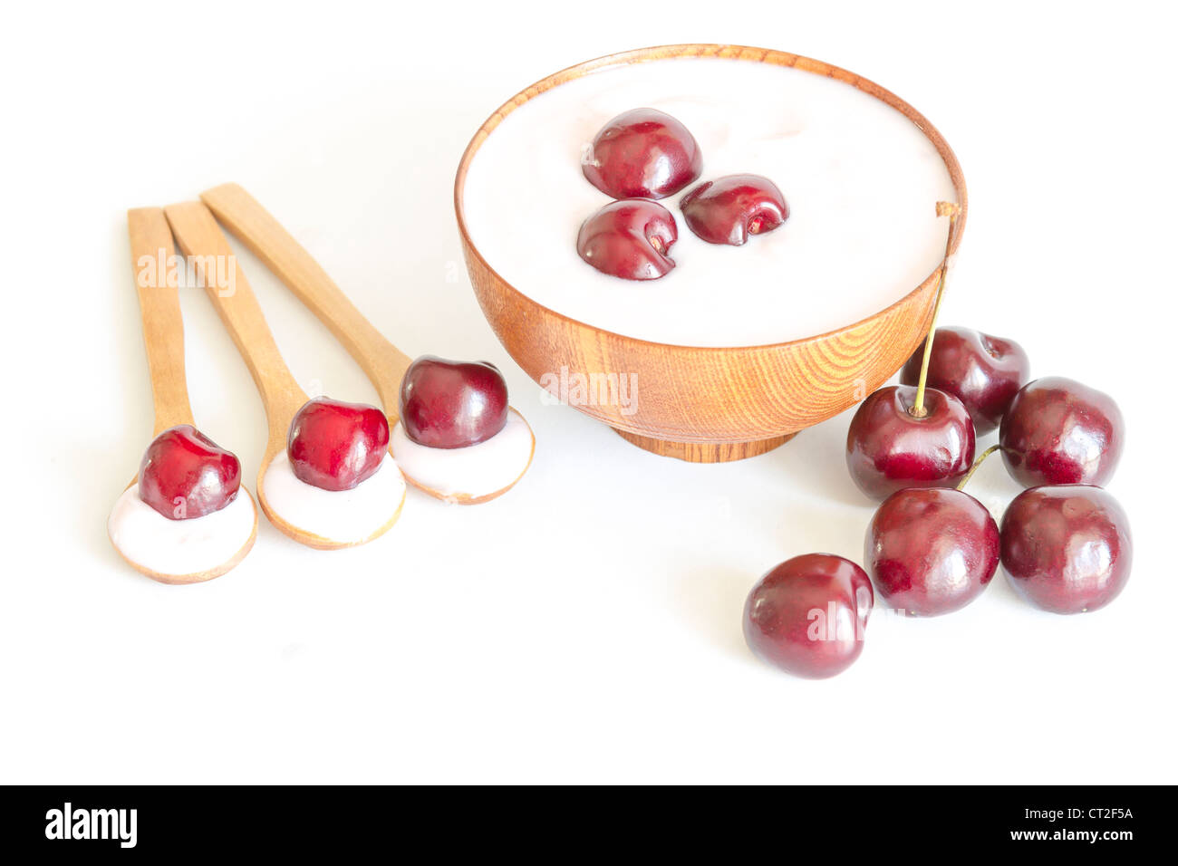 Vue de dessus d'un bol de cerises yaourt, cuillère en bois avec les cerises et le yogourt. Banque D'Images