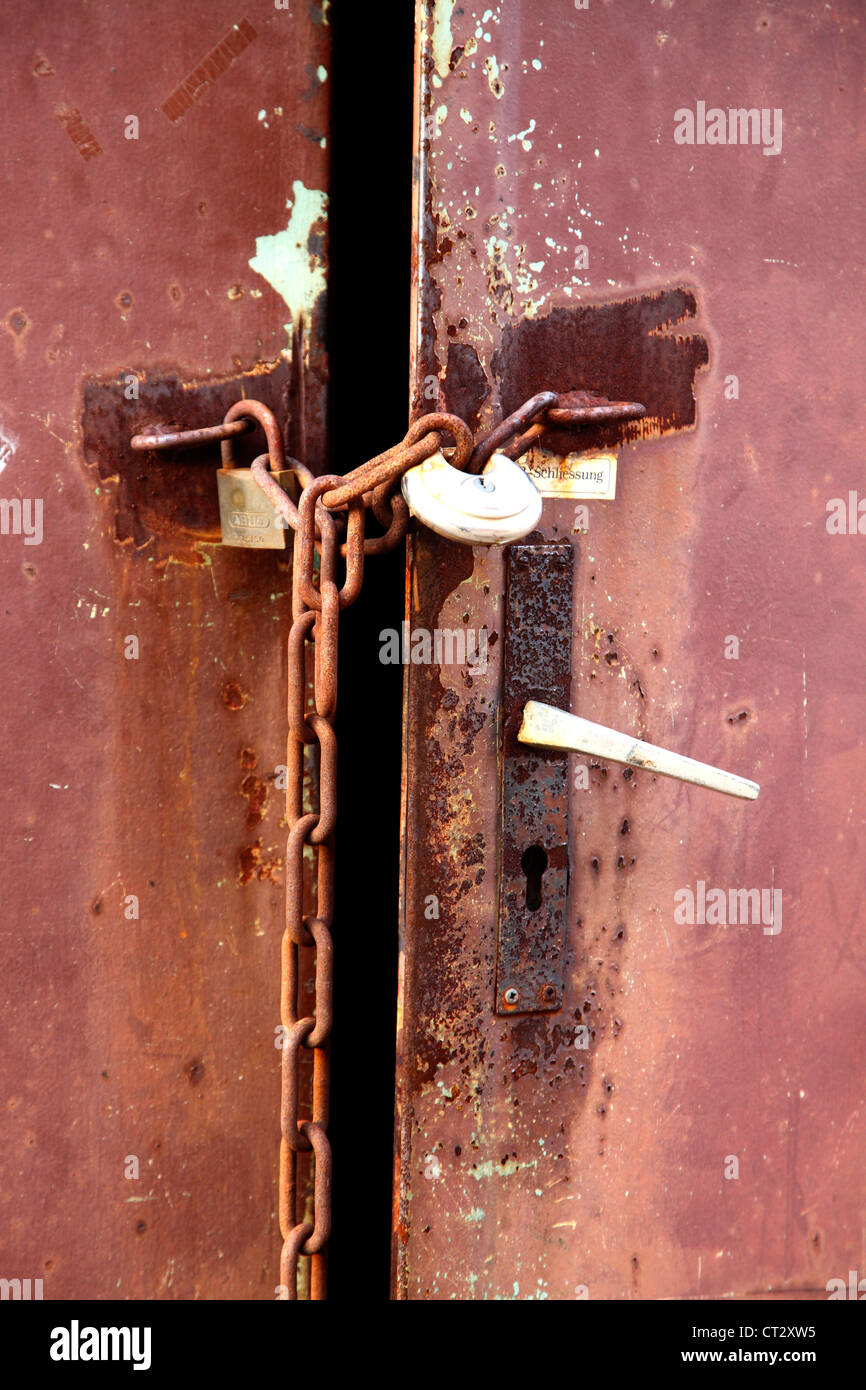 Rouge, métal rouillé, porte fermée avec une chaîne de fer. Banque D'Images