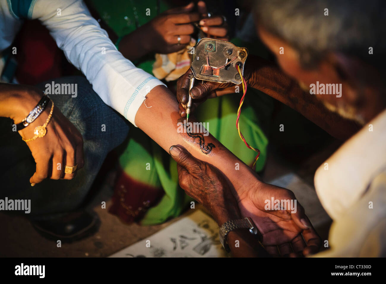 Jeune homme a tatouage encré sur son bras par tatoueur à juste rurales locales, Gujarat, Inde Banque D'Images