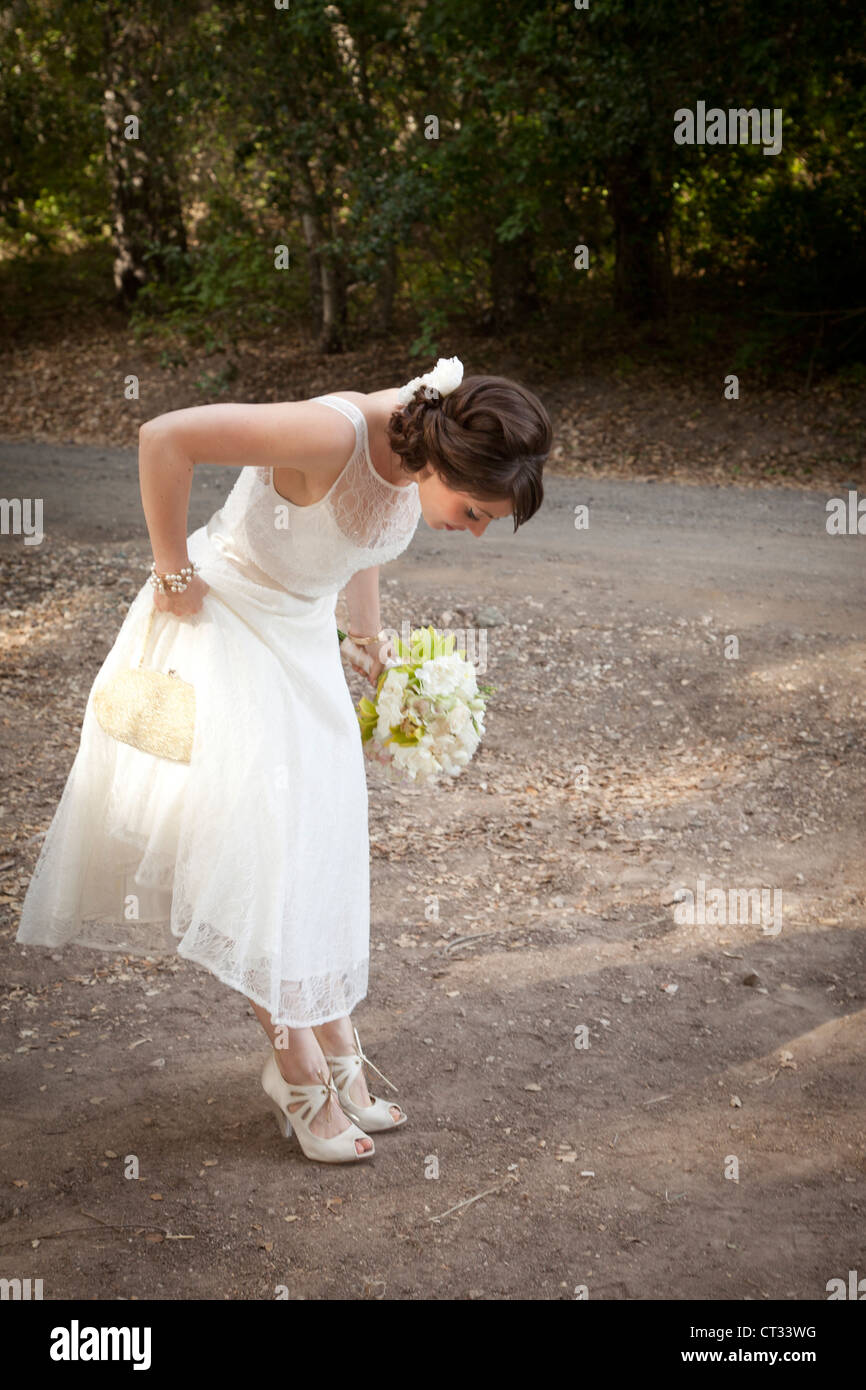 Mariée avec des fleurs en regardant ses chaussures. Banque D'Images