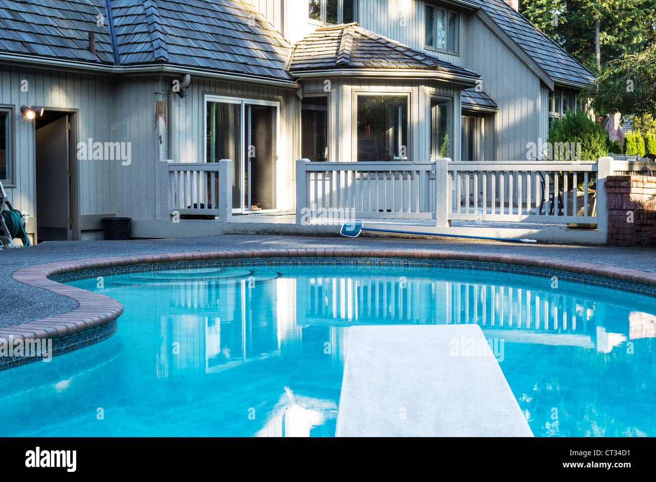 Piscine extérieure chauffée avec grande maison en arrière-plan avec des arbres verts Banque D'Images