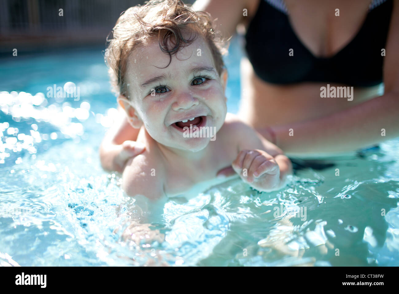 Petit garçon de nager dans une piscine retenus par sa mère Banque D'Images