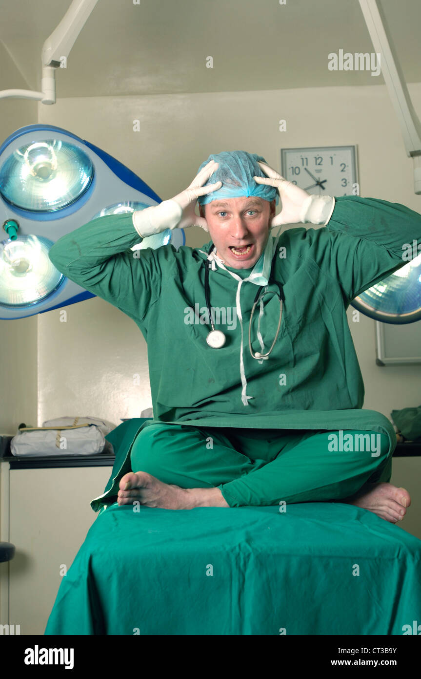 Un chirurgien assis jambes croisées sur la table d'opération crier avec les mains sur la tête Banque D'Images