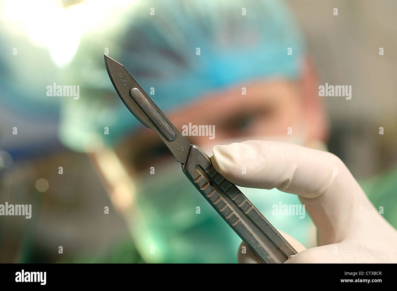 Un chirurgien holding up un scalpel stériles dans sa main gantée. Banque D'Images