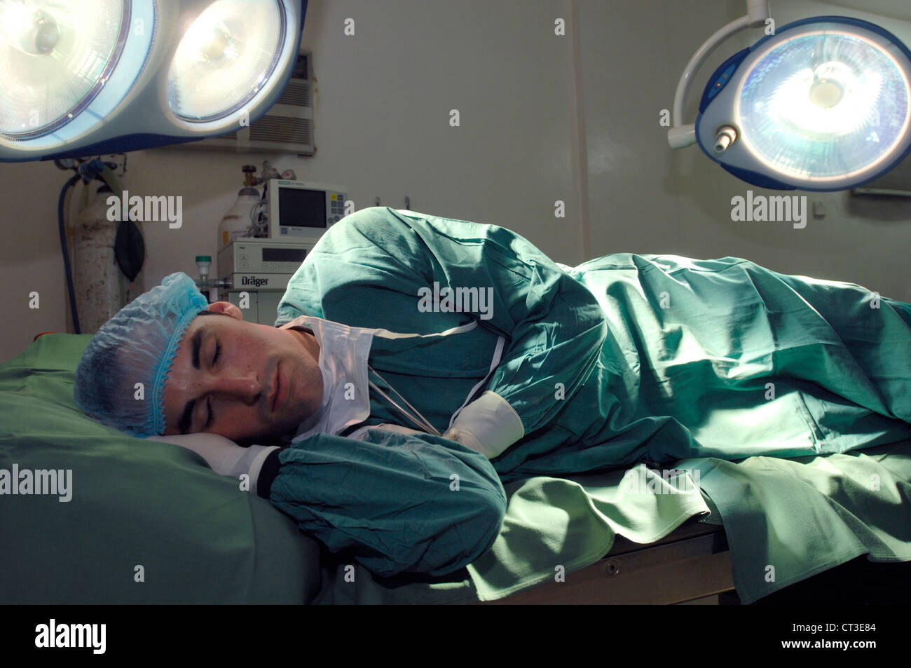 Un chirurgien épuisé endormi sur une table d'opération. Banque D'Images