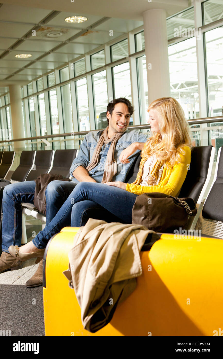 Couple talking in airport waiting area Banque D'Images