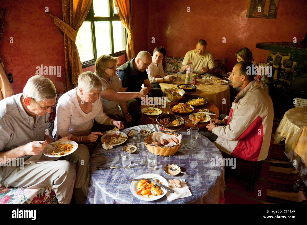 Les touristes ayant un repas à l'intérieur d'une maison berbère traditionnelle, Haut Atlas, Maroc Sud Banque D'Images