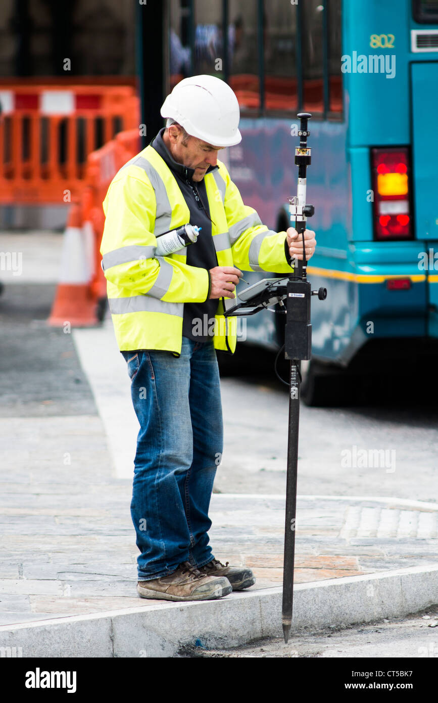 Un homme travaillant à l'extérieur, à l'aide d'un appareil GPS pour établir un projet de construction bâtiment UK Banque D'Images