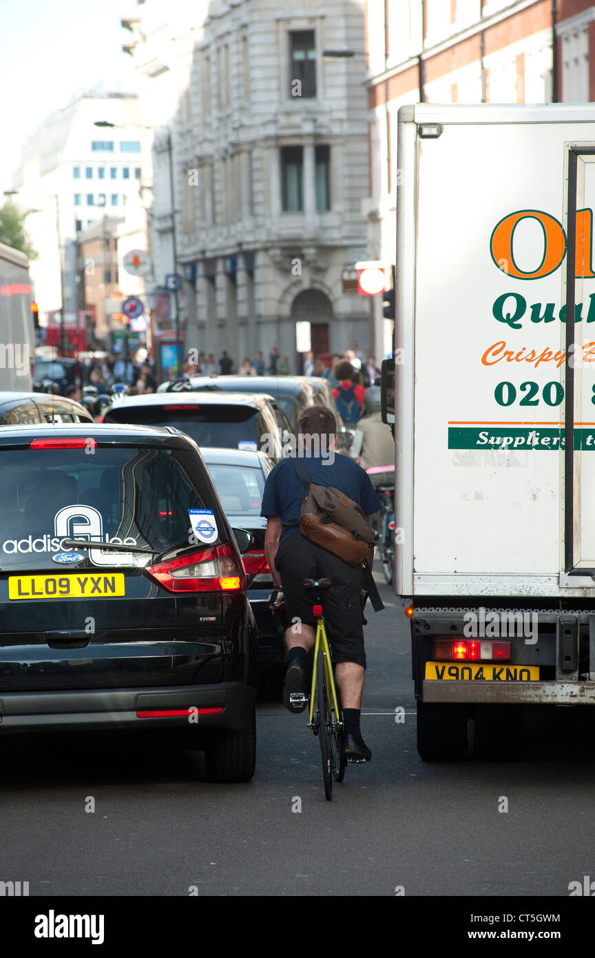 Compression cycliste entre véhicules d'attente dans le centre de la ville de Londres, en Angleterre. Banque D'Images