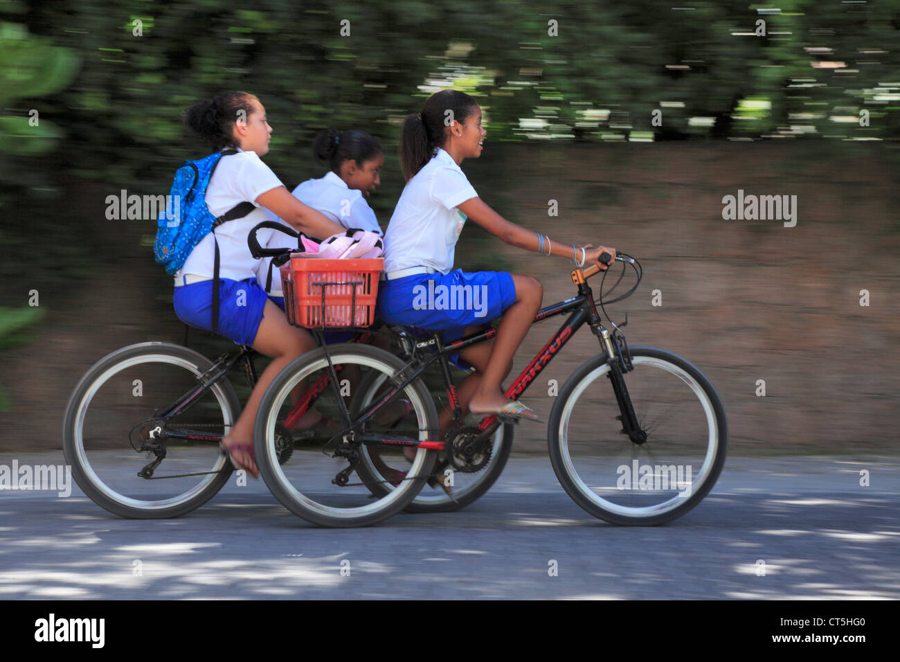 Trois jeunes filles faire du vélo à la maison de l'école sur l'île de La Digue aux Seychelles Banque D'Images