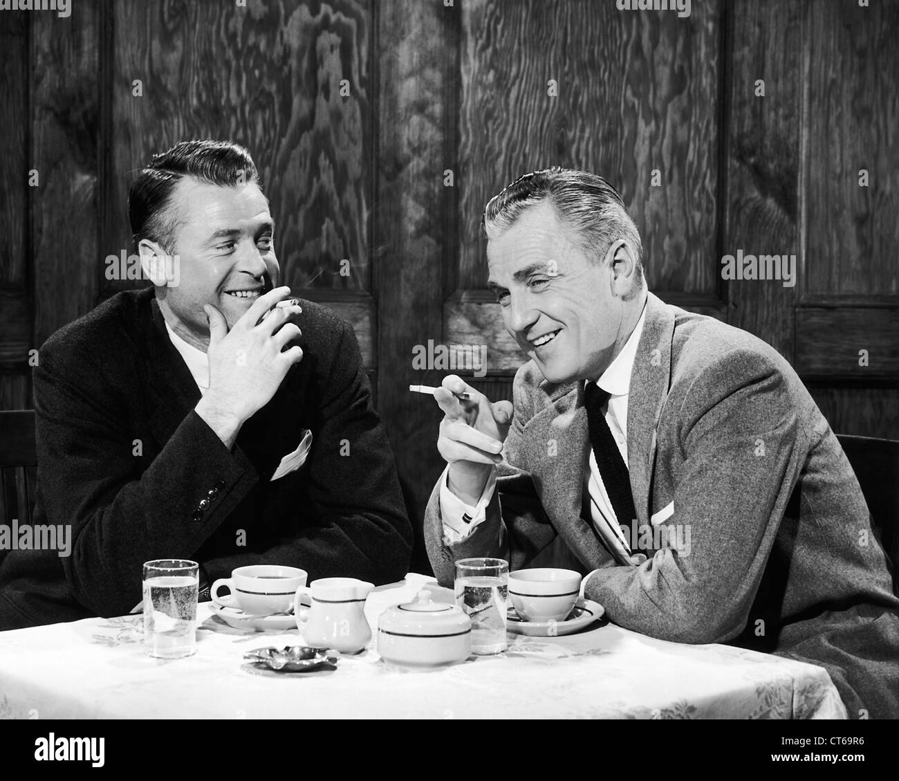 Hommes d'fumer des cigarettes et en souriant le dîner Banque D'Images